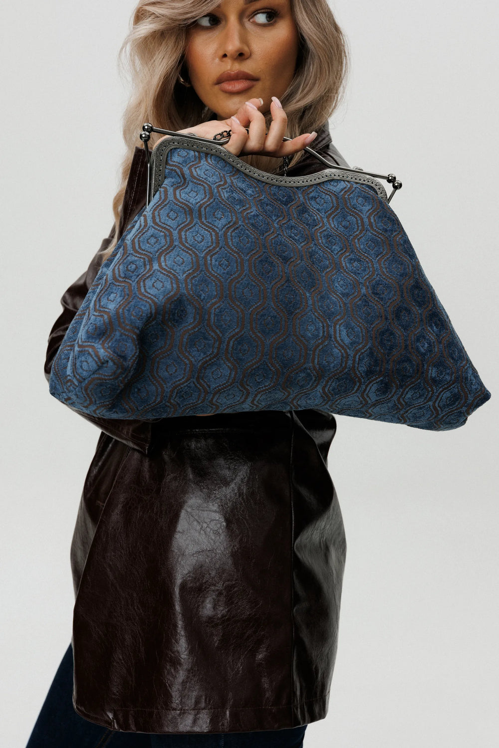 Woman holding a blue patterned handbag against a white background