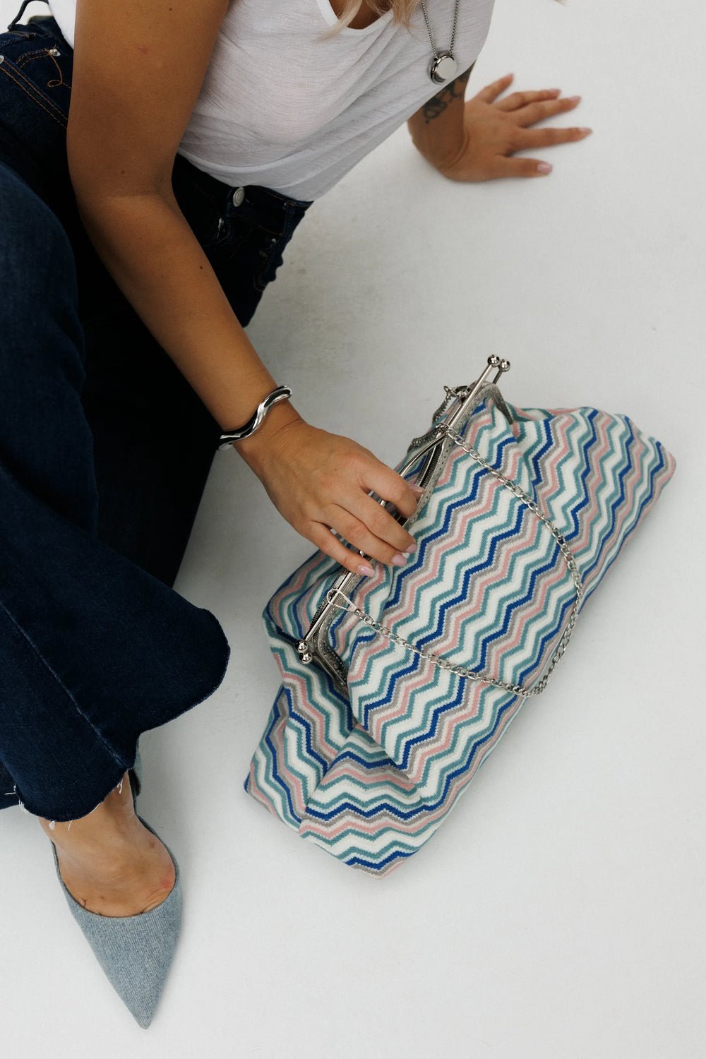 Person holding a patterned handbag on a white floor