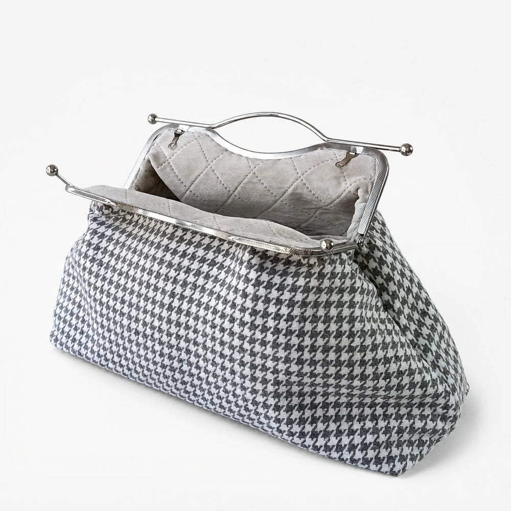 Houndstooth patterned handbag with a metallic clasp on a white background