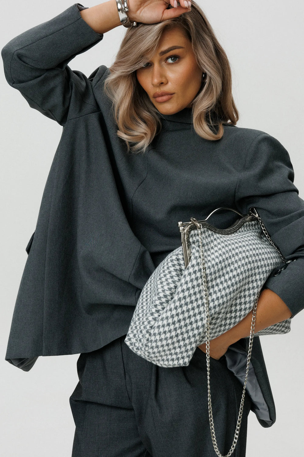 Woman holding a houndstooth patterned handbag against a plain background