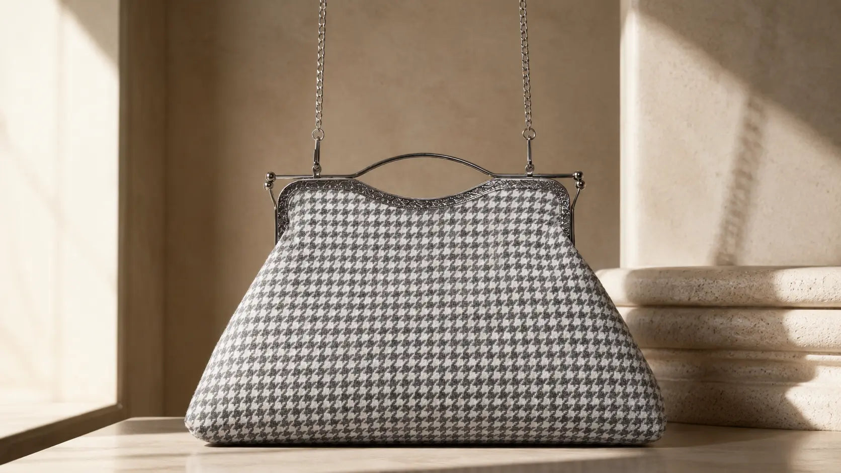 Houndstooth patterned handbag with a chain strap on a neutral background