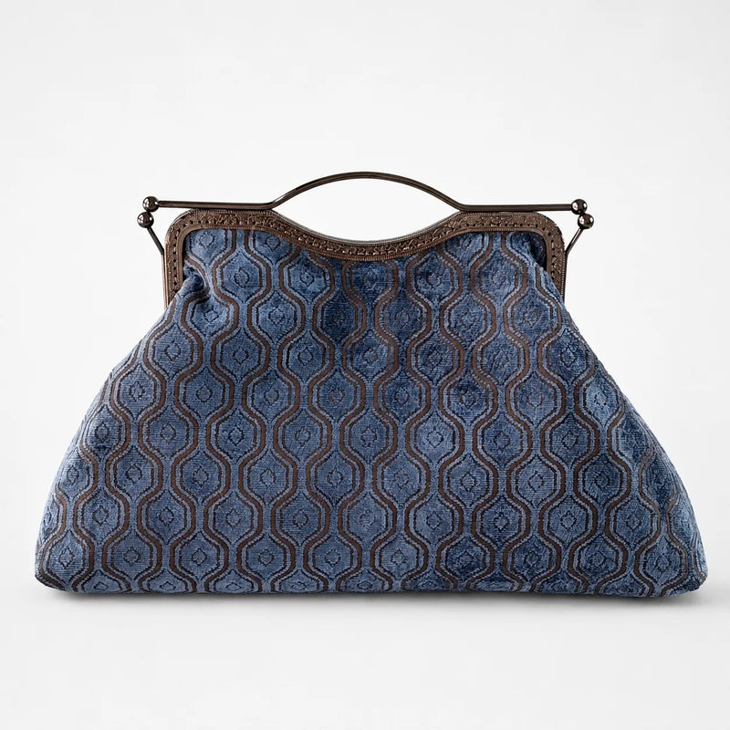 Blue patterned handbag with a brown handle on a white background