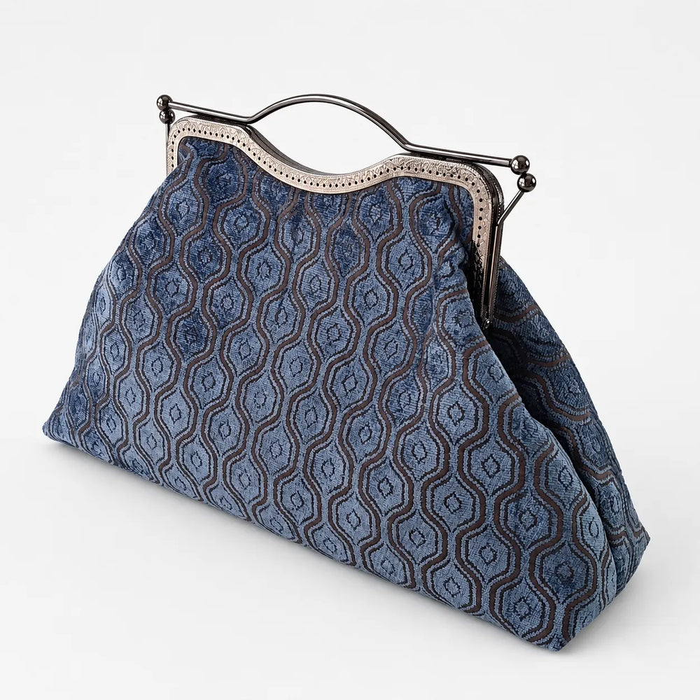Blue patterned handbag with a metal frame on a white background