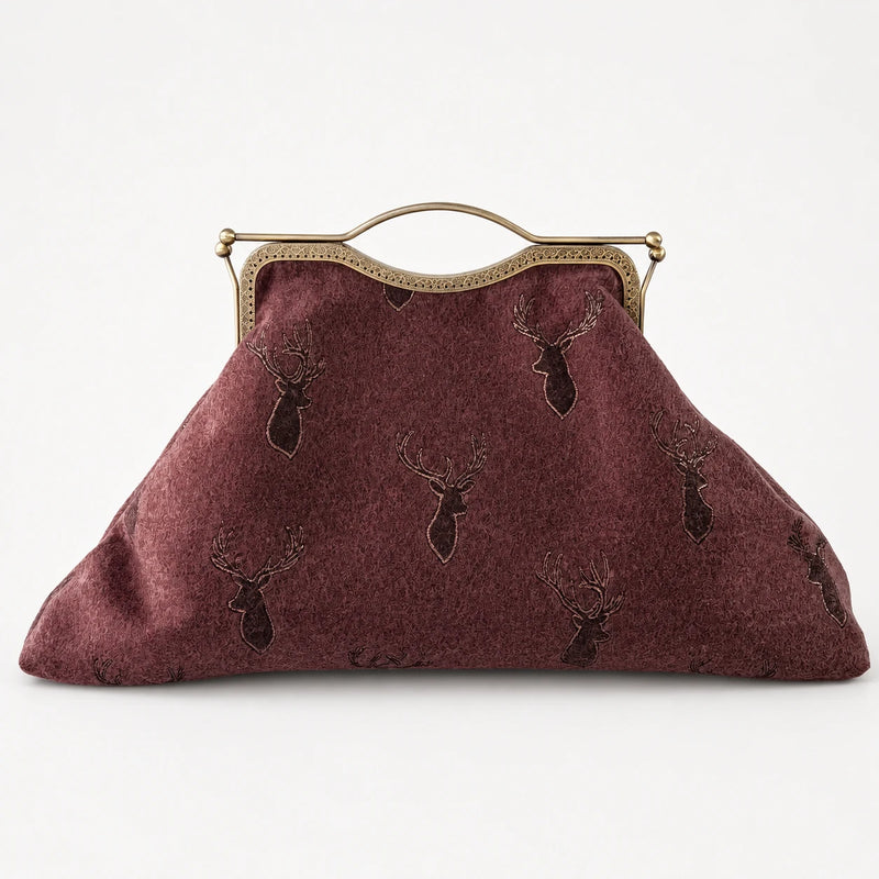 Brown textured handbag with deer head design and gold frame on a white background