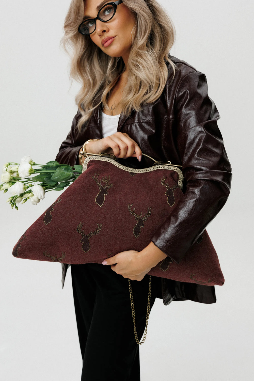 Woman holding a brown clutch with deer patterns against a white background