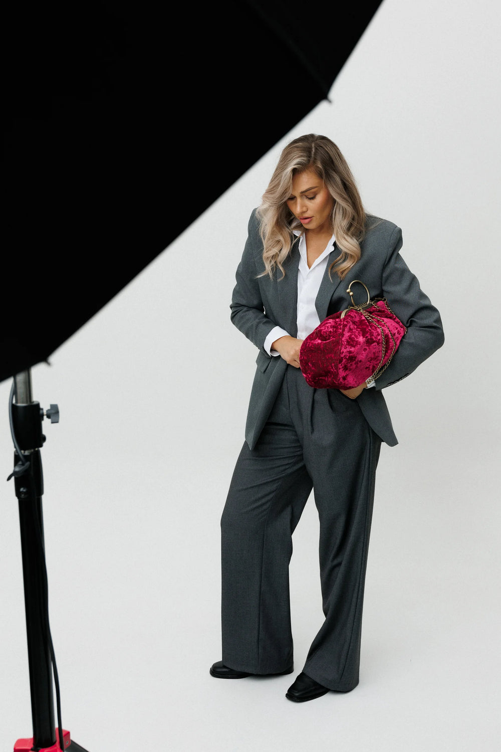 Woman in a gray suit holding a red velvet bag