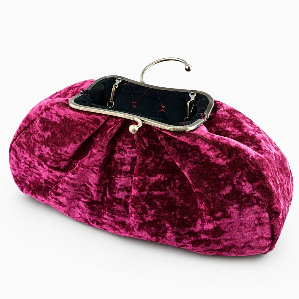 Pink velvet clutch bag with a black interior on a white background