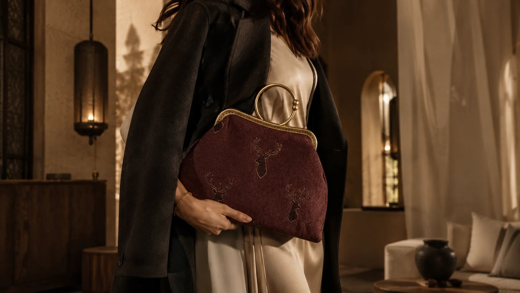 Person holding a maroon handbag in an indoor setting with warm lighting