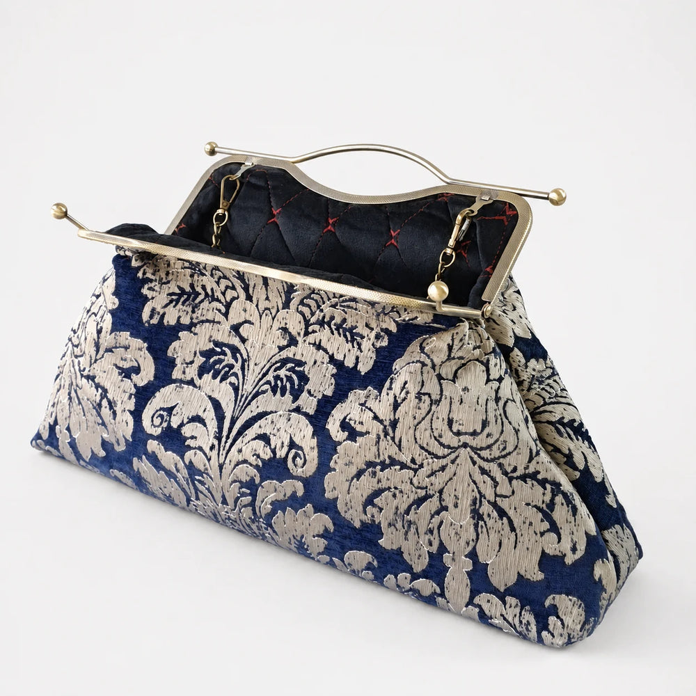 Blue and white patterned clutch bag with gold clasp on a white background