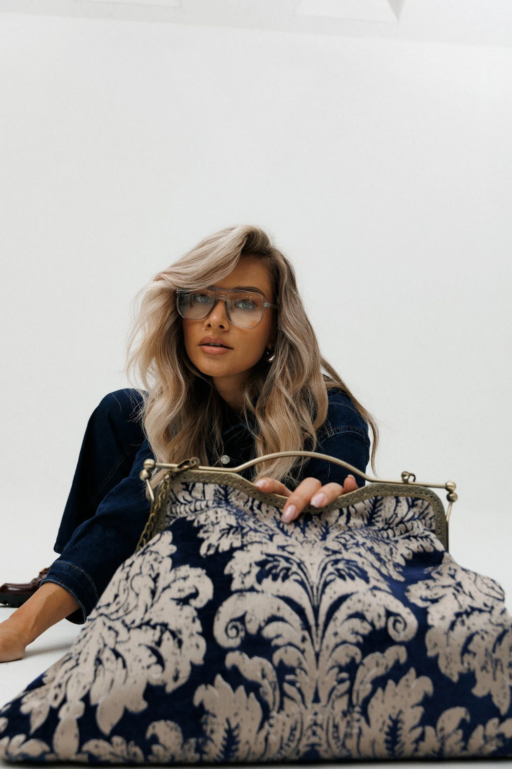 Woman holding a blue and white patterned handbag against a white background