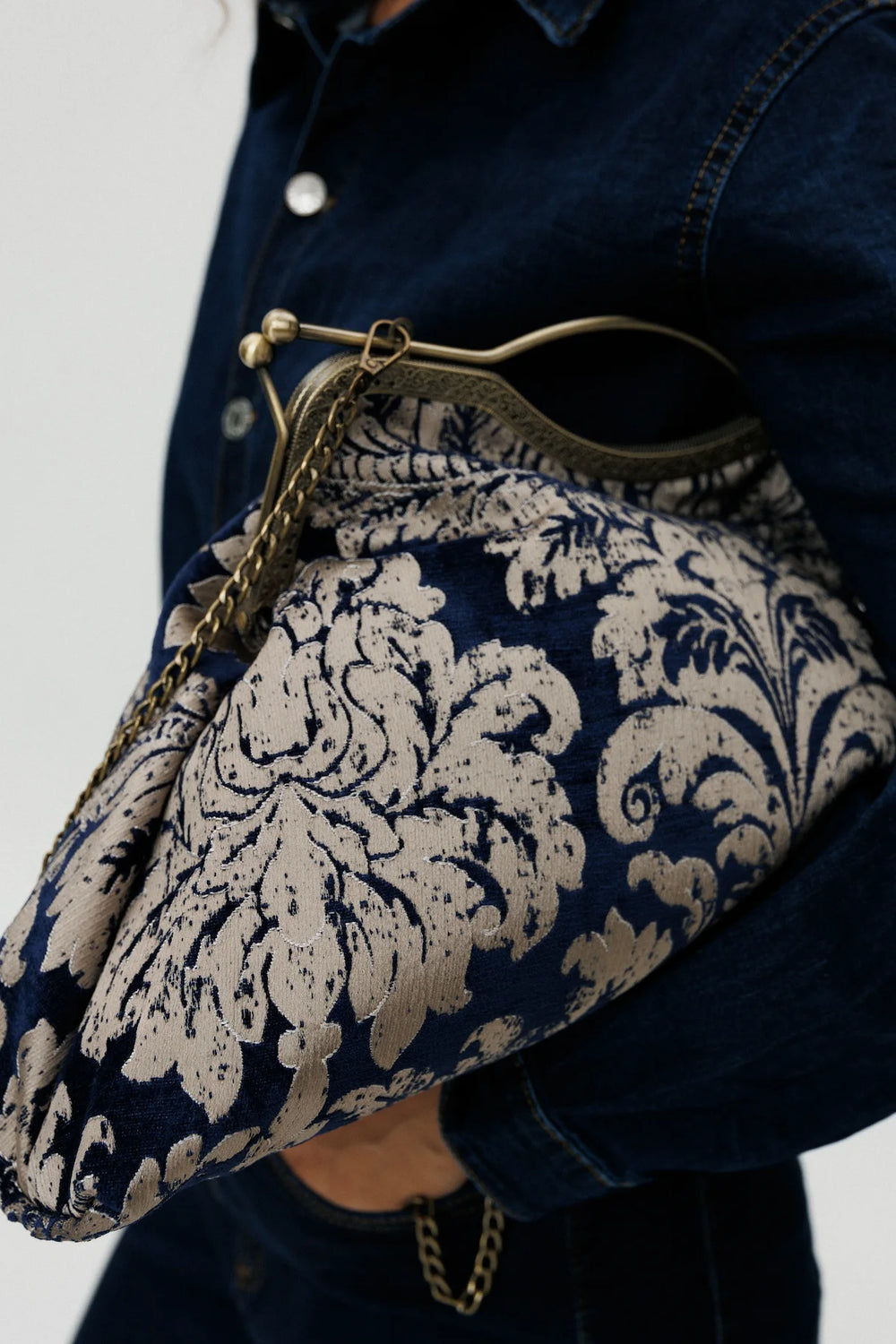 Person holding a blue and white patterned handbag with a plain background